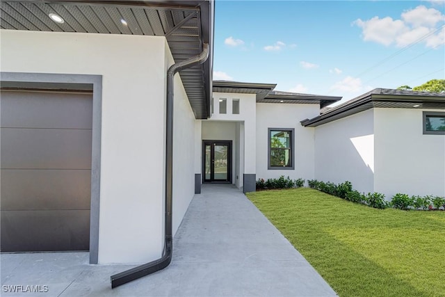 property entrance with a garage, a lawn, and stucco siding