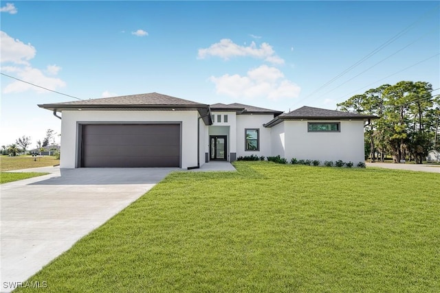 prairie-style home with a garage, stucco siding, concrete driveway, and a front yard