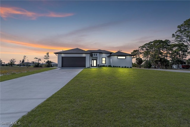 prairie-style house with a garage, concrete driveway, and a lawn