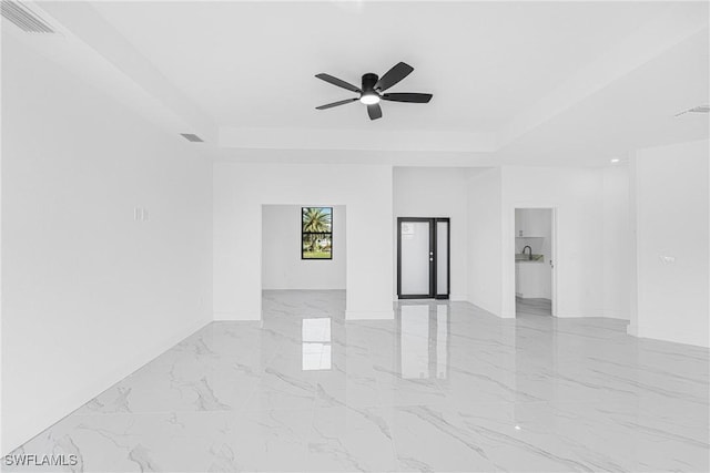 spare room featuring marble finish floor, a raised ceiling, visible vents, ceiling fan, and baseboards