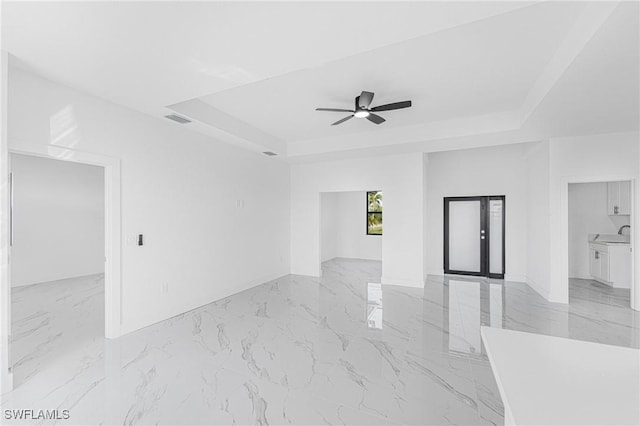 spare room featuring marble finish floor, visible vents, a raised ceiling, and a sink