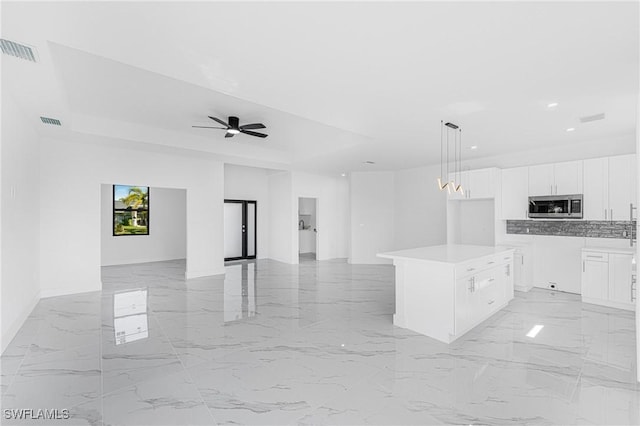 kitchen featuring visible vents, stainless steel microwave, open floor plan, marble finish floor, and white cabinetry