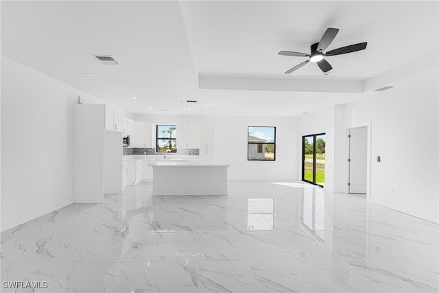 unfurnished living room with marble finish floor, plenty of natural light, and visible vents