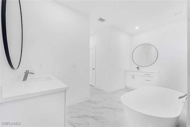 full bath with visible vents, a sink, marble finish floor, a freestanding tub, and two vanities