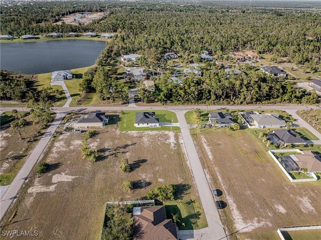 birds eye view of property featuring a forest view, a water view, and a residential view