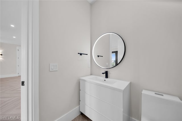 half bathroom featuring recessed lighting, toilet, vanity, and baseboards