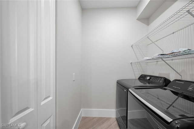 laundry room featuring laundry area, baseboards, washer and clothes dryer, and light wood-style floors