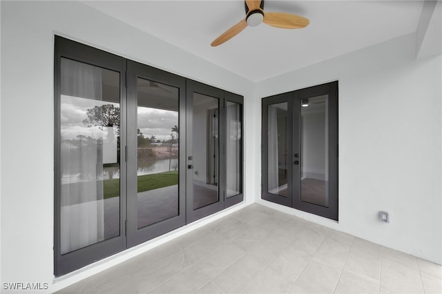 exterior space with a water view, a ceiling fan, and french doors