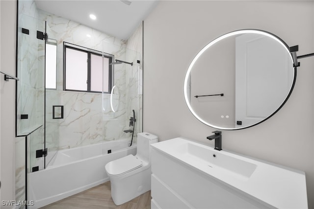 full bath with bath / shower combo with glass door, recessed lighting, toilet, vanity, and wood finished floors