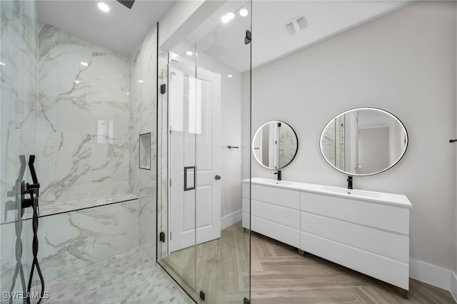 bathroom with double vanity, a sink, a marble finish shower, and baseboards