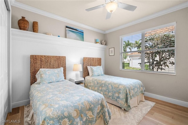 bedroom featuring ceiling fan, crown molding, baseboards, and wood finished floors