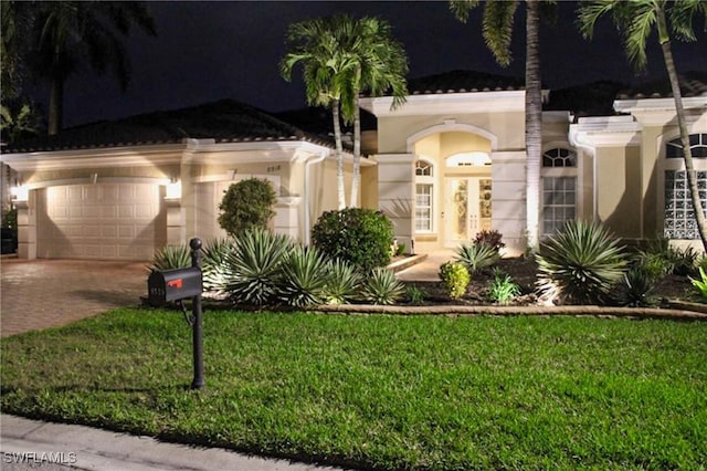 view of front of home with a garage, decorative driveway, a front lawn, and stucco siding