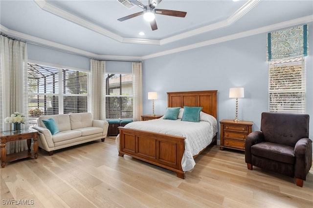 bedroom featuring crown molding, a raised ceiling, visible vents, and light wood-style floors