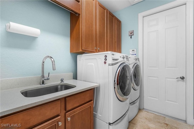 clothes washing area featuring washing machine and dryer, cabinet space, and a sink