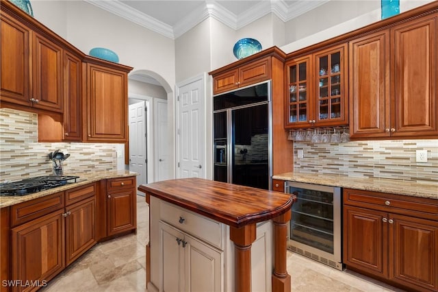 kitchen featuring arched walkways, wine cooler, built in refrigerator, wood counters, and crown molding