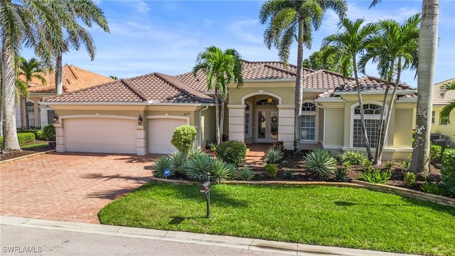 mediterranean / spanish home with decorative driveway, french doors, stucco siding, an attached garage, and a tiled roof