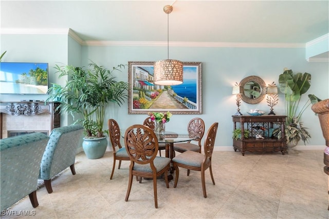 dining space with tile patterned flooring, a fireplace, baseboards, and crown molding