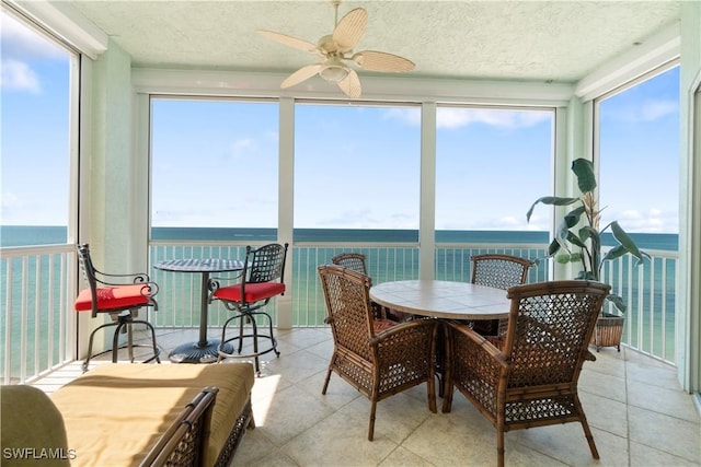 sunroom / solarium featuring a water view and a ceiling fan