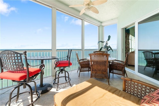 sunroom / solarium with a water view and a ceiling fan