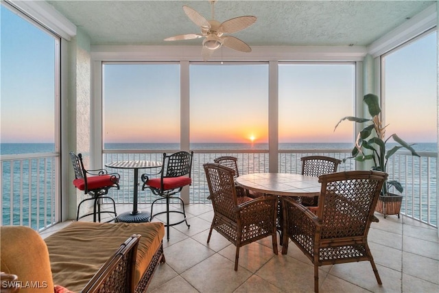 sunroom featuring a water view, a ceiling fan, and a healthy amount of sunlight