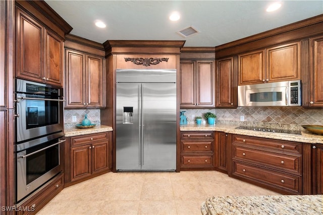 kitchen with light tile patterned floors, visible vents, decorative backsplash, light stone counters, and stainless steel appliances