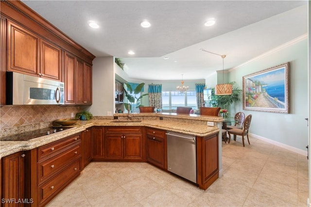 kitchen featuring appliances with stainless steel finishes, light stone counters, a peninsula, a sink, and a notable chandelier