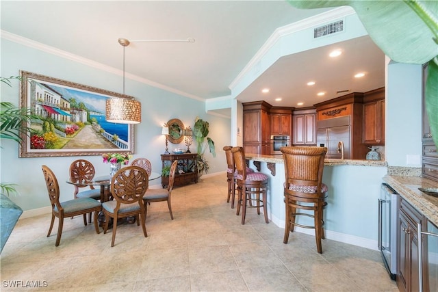 dining room with beverage cooler, ornamental molding, visible vents, and baseboards