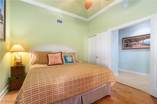 bedroom featuring ornamental molding, visible vents, baseboards, and wood finished floors