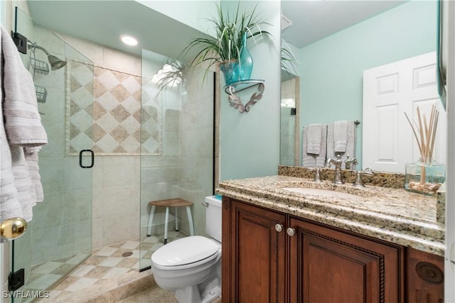 bathroom with toilet, a stall shower, and vanity