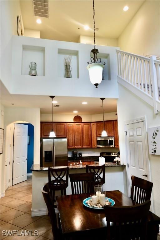 dining space featuring visible vents, a towering ceiling, and stairs