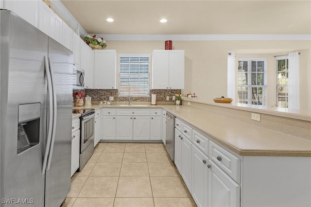 kitchen featuring tasteful backsplash, white cabinetry, appliances with stainless steel finishes, a peninsula, and light tile patterned floors