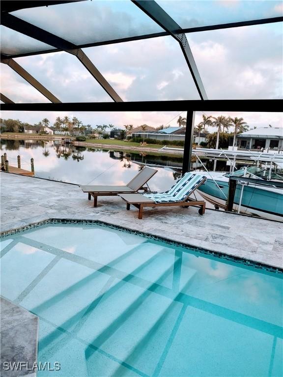 view of pool featuring a patio area, a lanai, and a water view