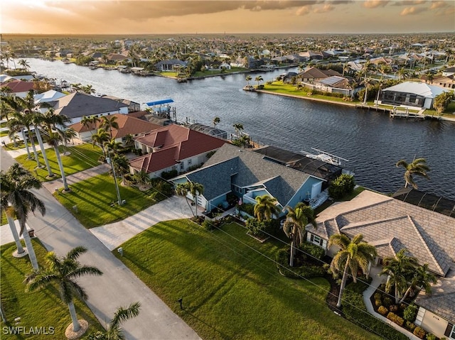 aerial view at dusk featuring a residential view and a water view