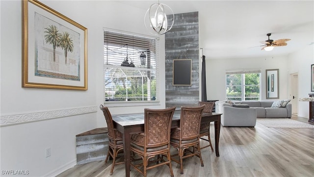 dining area with wood finished floors and ceiling fan with notable chandelier