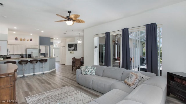 living room featuring a ceiling fan, light wood-type flooring, visible vents, and recessed lighting