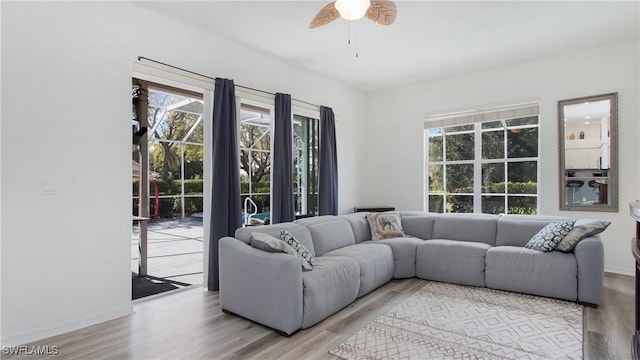 living area with a healthy amount of sunlight, ceiling fan, baseboards, and wood finished floors