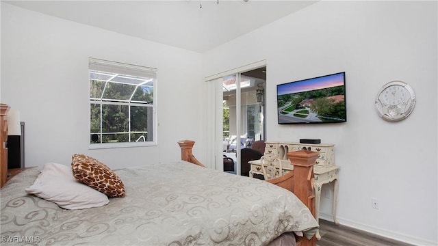 bedroom with access to exterior, multiple windows, and wood finished floors