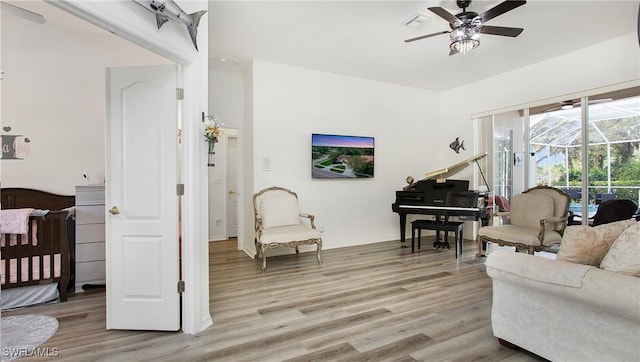 living area with a sunroom, visible vents, ceiling fan, and light wood-style flooring