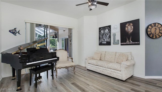 sitting room with a ceiling fan, baseboards, and wood finished floors