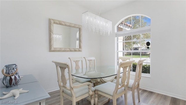 dining room with a chandelier, wood finished floors, and baseboards