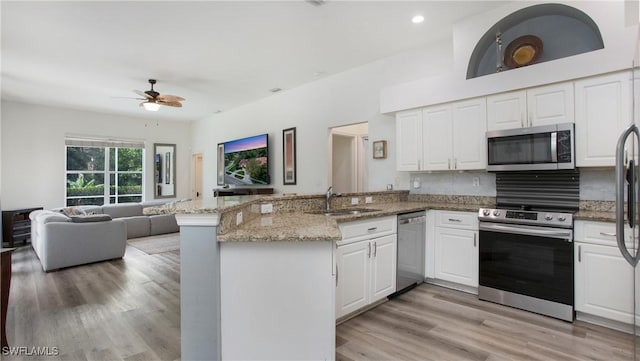 kitchen with stainless steel appliances, a peninsula, a sink, white cabinets, and open floor plan