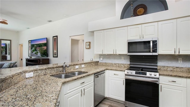 kitchen featuring light stone countertops, appliances with stainless steel finishes, decorative backsplash, and a sink