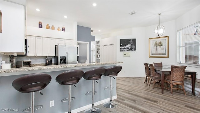 kitchen with white cabinetry, visible vents, stainless steel appliances, and a kitchen breakfast bar