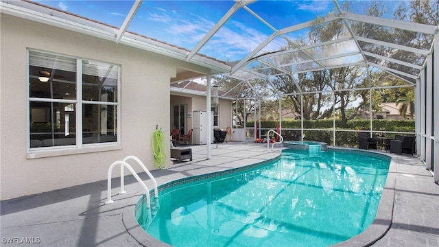 view of pool with glass enclosure, a patio area, and a pool with connected hot tub