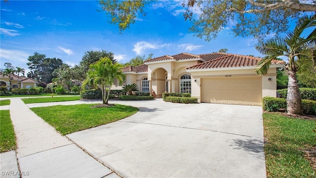 mediterranean / spanish home with stucco siding, concrete driveway, a garage, a tiled roof, and a front lawn