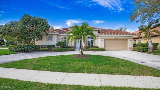 mediterranean / spanish house featuring a tile roof, stucco siding, an attached garage, driveway, and a front lawn