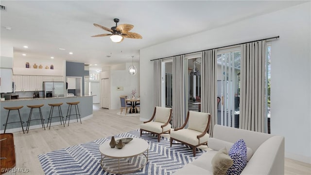 living room with light wood-type flooring, visible vents, a ceiling fan, and recessed lighting