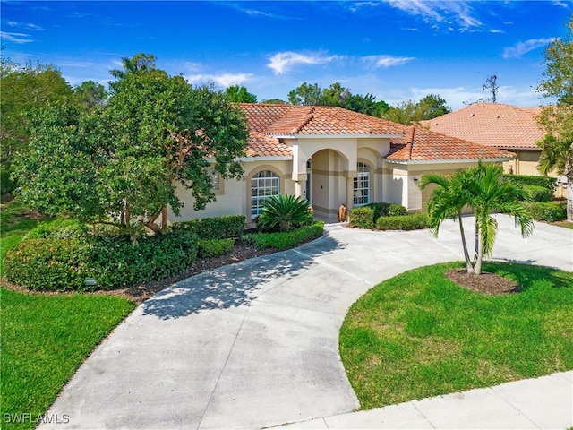 mediterranean / spanish house featuring a front yard, a tile roof, driveway, and stucco siding