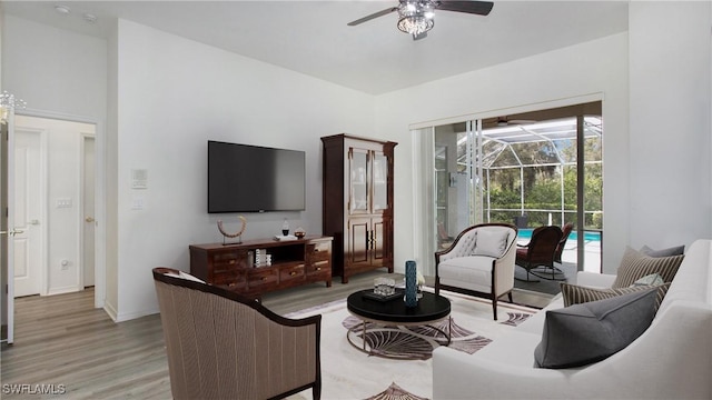 living area featuring light wood-type flooring, a sunroom, baseboards, and a ceiling fan