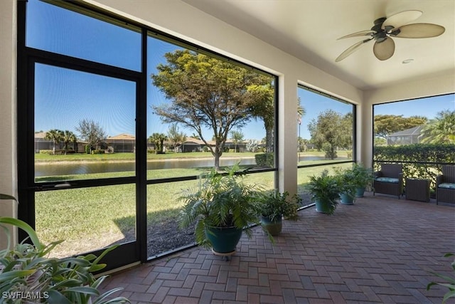 unfurnished sunroom with a water view and ceiling fan